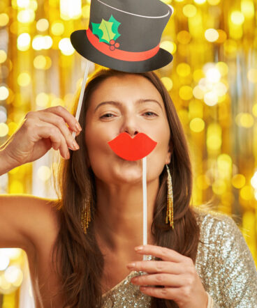 Young woman over gold background with photo booth accessories